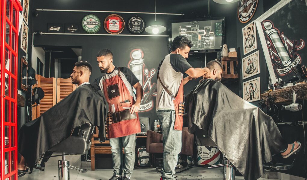 A bustling barbershop with two men getting haircuts, showcasing a vibrant barber environment.