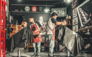 A bustling barbershop with two men getting haircuts, showcasing a vibrant barber environment.