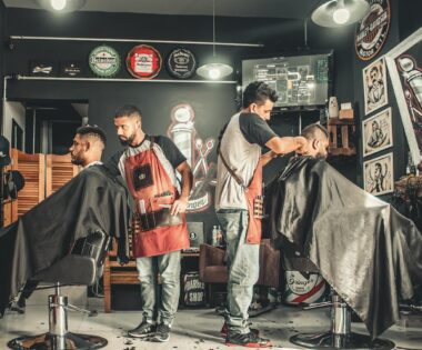 A bustling barbershop with two men getting haircuts, showcasing a vibrant barber environment.