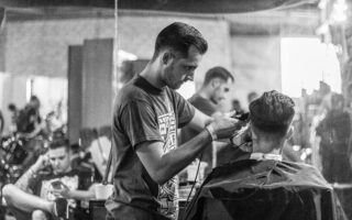 A barber skillfully gives a haircut in a stylish Wrocław barbershop, captured in moody monochrome. U ACADEMY