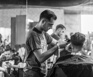 A barber skillfully gives a haircut in a stylish Wrocław barbershop, captured in moody monochrome. U ACADEMY