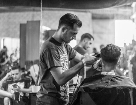 A barber skillfully gives a haircut in a stylish Wrocław barbershop, captured in moody monochrome. U ACADEMY