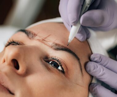 A beautician performs precise microblading on a client's eyebrows in a salon. Permanent Makeup