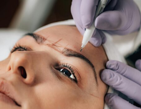 A beautician performs precise microblading on a client's eyebrows in a salon. Permanent Makeup