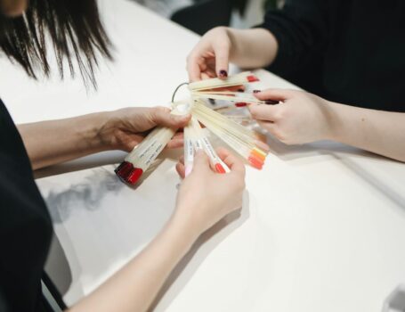 Close-up of hands selecting gel polish colors in a nail salon.